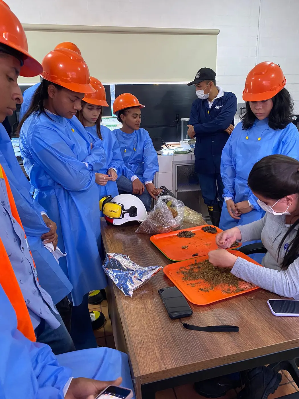 Jóvenes con batas y cascos en una visita empresarial